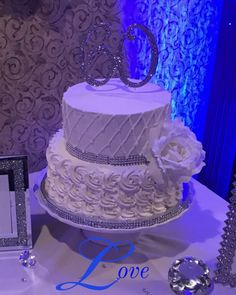 a white wedding cake sitting on top of a table next to a blue and silver wall