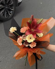 a bouquet of flowers is being held by someone's hand on the street corner