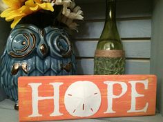 a wooden sign that says hope next to a vase with flowers and an owl statue