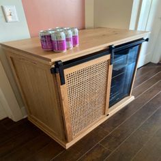 four cans of soda sitting on top of a wooden cabinet