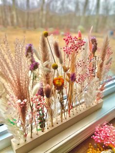 some flowers and plants are sitting on a window sill in front of a window