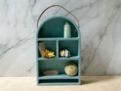 a blue shelf with various items on it in front of a marble wall and floor