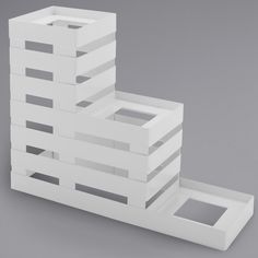 a stack of white boxes sitting on top of each other in front of a gray wall