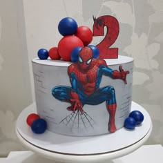 a spiderman birthday cake with red, white and blue balloons on top is shown