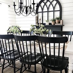 the dining room table is set with black chairs and white flowers in vases on it