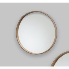 two round mirrors with gold rims on the wall