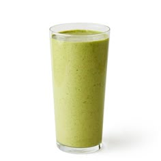 a glass filled with green smoothie sitting on top of a table