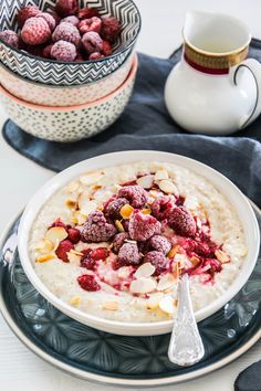 a bowl of oatmeal topped with raspberries and almonds next to a cup of coffee