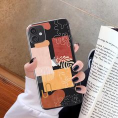 a woman holding up her phone case while reading a book