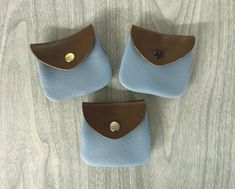 three small blue and brown purses sitting on top of a wooden table next to each other