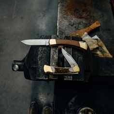 a knife is sitting on top of a piece of wood with two knives in it