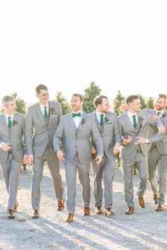 a group of men standing next to each other wearing gray suits and green tie ties