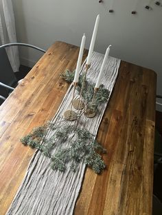 a wooden table topped with candles and greenery on top of it's sides