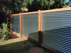 a fence that is made out of metal sheets and wood slats, in the backyard