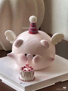 a cake shaped like a pig with wings and a birthday hat on it's head