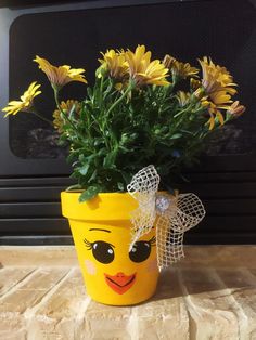 a yellow flower pot with flowers in it