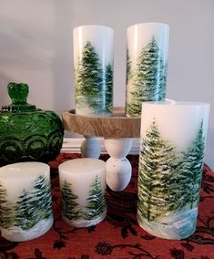 a table topped with candles and vases covered in frosty green pine tree designs