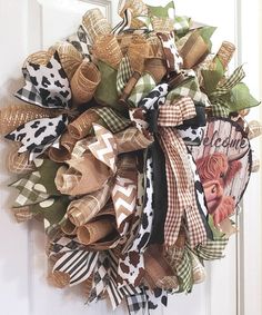 a wreath is hanging on the front door, decorated with cow print ribbon and bows