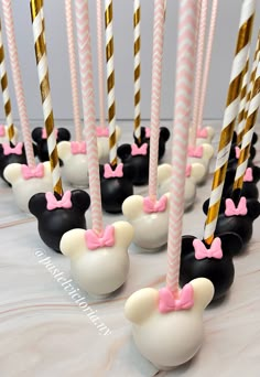 mickey mouse cake pops are lined up with pink and white striped straws on them