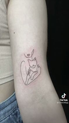 a woman's arm with a small cat tattoo on the left side of her body