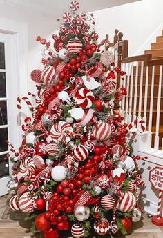 a christmas tree decorated with candy canes, ornaments and greenery in red and white