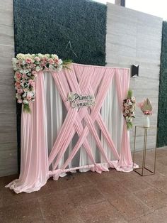 a pink and white wedding ceremony backdrop with flowers on the top, along with an aisle