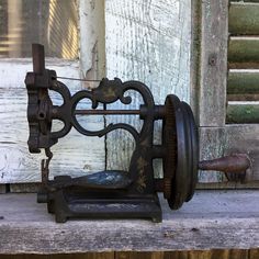 an old sewing machine sitting on top of a wooden table next to a window with shutters