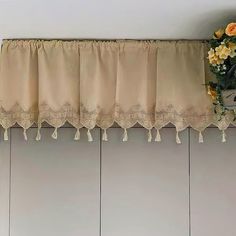 the curtains are hanging on the wall above the window sill with flowers in front of them