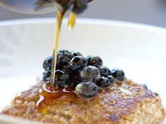 pancakes with blueberries and syrup being drizzled on top