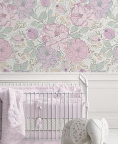 a baby's crib with pink flowers on the wall behind it and a teddy bear