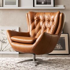 a brown leather chair sitting on top of a rug next to a wall with pictures