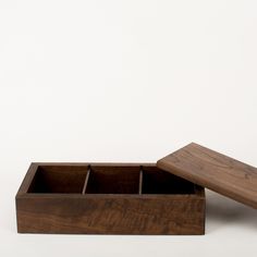 a wooden box sitting on top of a white floor next to a brown object with two compartments