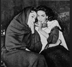 two women sitting next to each other in black and white, one is holding her hand on her face