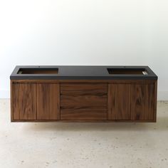 a large wooden cabinet with two sinks on it's sides, against a white wall