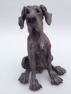 a statue of a dog sitting on the ground with one paw up in the air