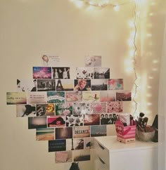 a white dresser sitting next to a wall covered in pictures and lights on top of it