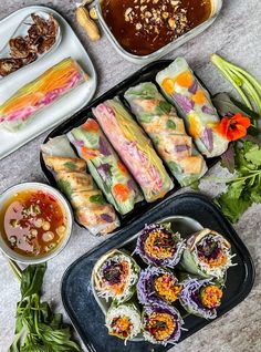 an assortment of sushi and other food items laid out on a counter top with dipping sauces