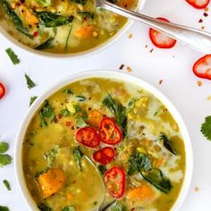 two bowls filled with soup on top of a white table next to red peppers and cilantro