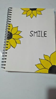 a spiral notebook with sunflowers and the word smile written on it in black ink