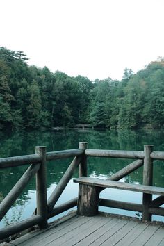 a wooden bench sitting on top of a pier next to a body of water with trees in the background