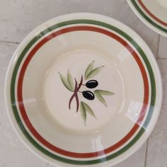 two plates with olives painted on them are sitting on the floor next to each other