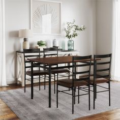 a dining room table with four chairs and a vase