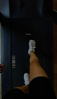 a person standing on top of a scale with their feet in the air next to a clock