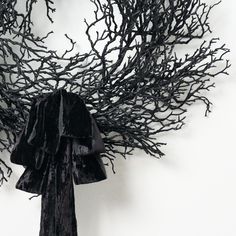 a black scarf hanging on the wall next to a bunch of branches that have been tied together