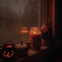 two pumpkins sitting on a window sill next to jars with candles in them