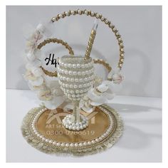 a white vase with pearls and flowers on top of a gold plated coin holder