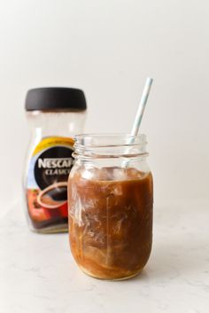 a jar filled with liquid sitting on top of a counter next to a bottle of peanut butter