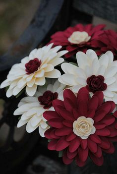 red and white flowers sitting on top of a wooden bench