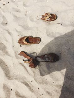 three pairs of shoes are sitting in the sand