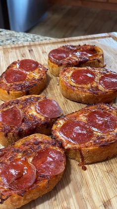 several pepperoni pizzas are on a cutting board